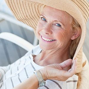 woman smiling wearing a beach hat